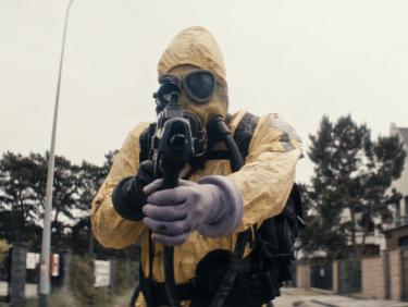 Man in hazmat suit pointing gun into camera